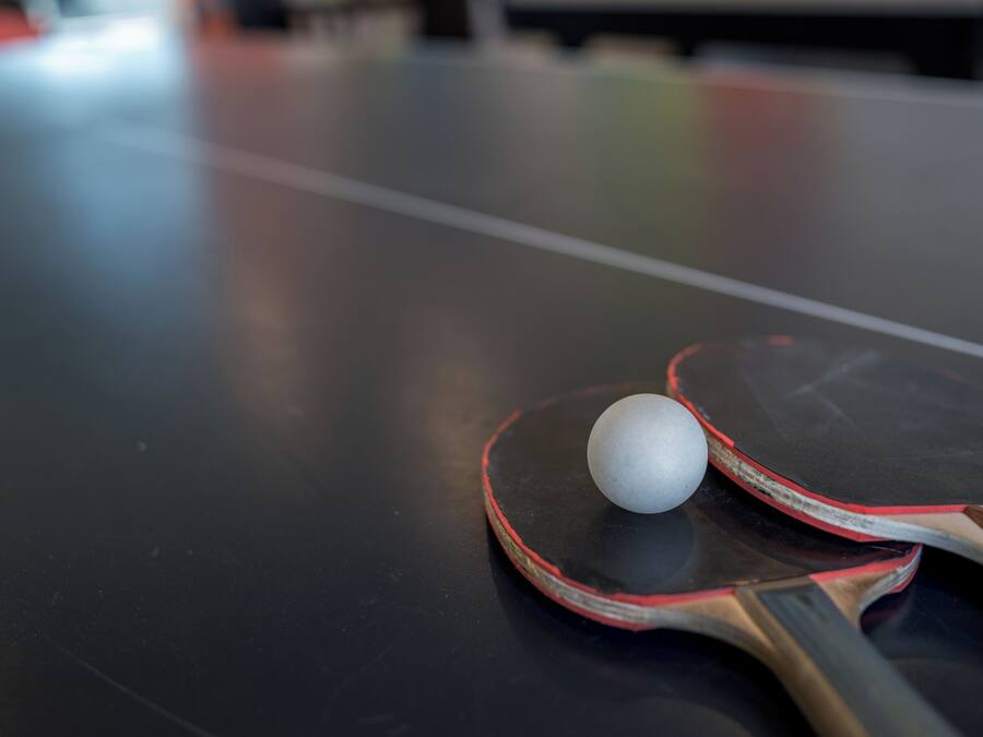 Primer plano de una mesa de tenis de mesa con una raqueta y una pelota.