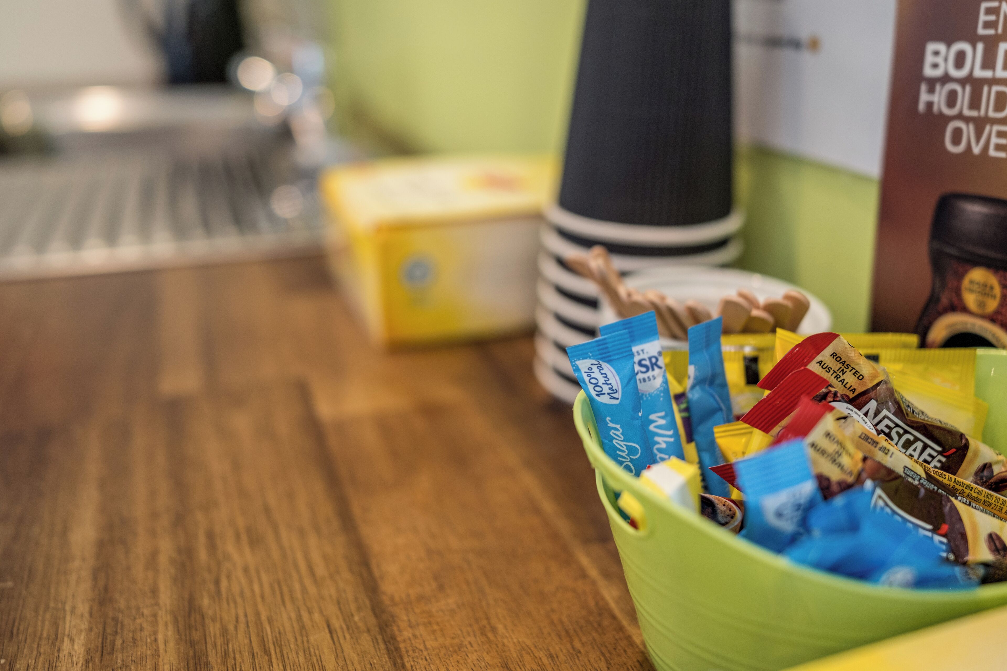A kitchen counter with a green bowl containing various packaged food items.