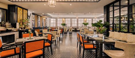 A spacious restaurant with high ceilings, multiple dining areas, and a patterned floor.