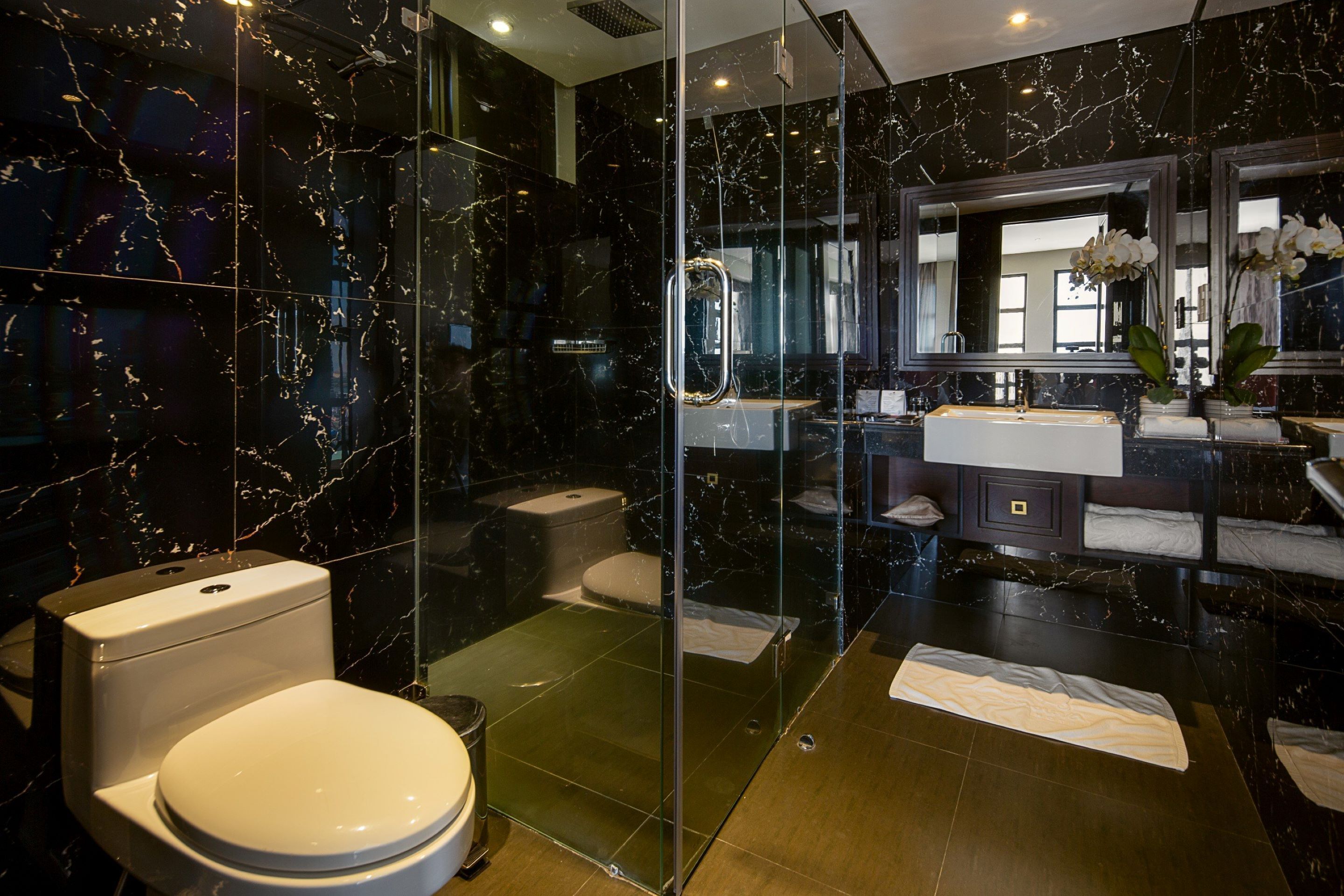 A modern bathroom with a glass-enclosed shower, a white toilet, and a vanity with a mirror.