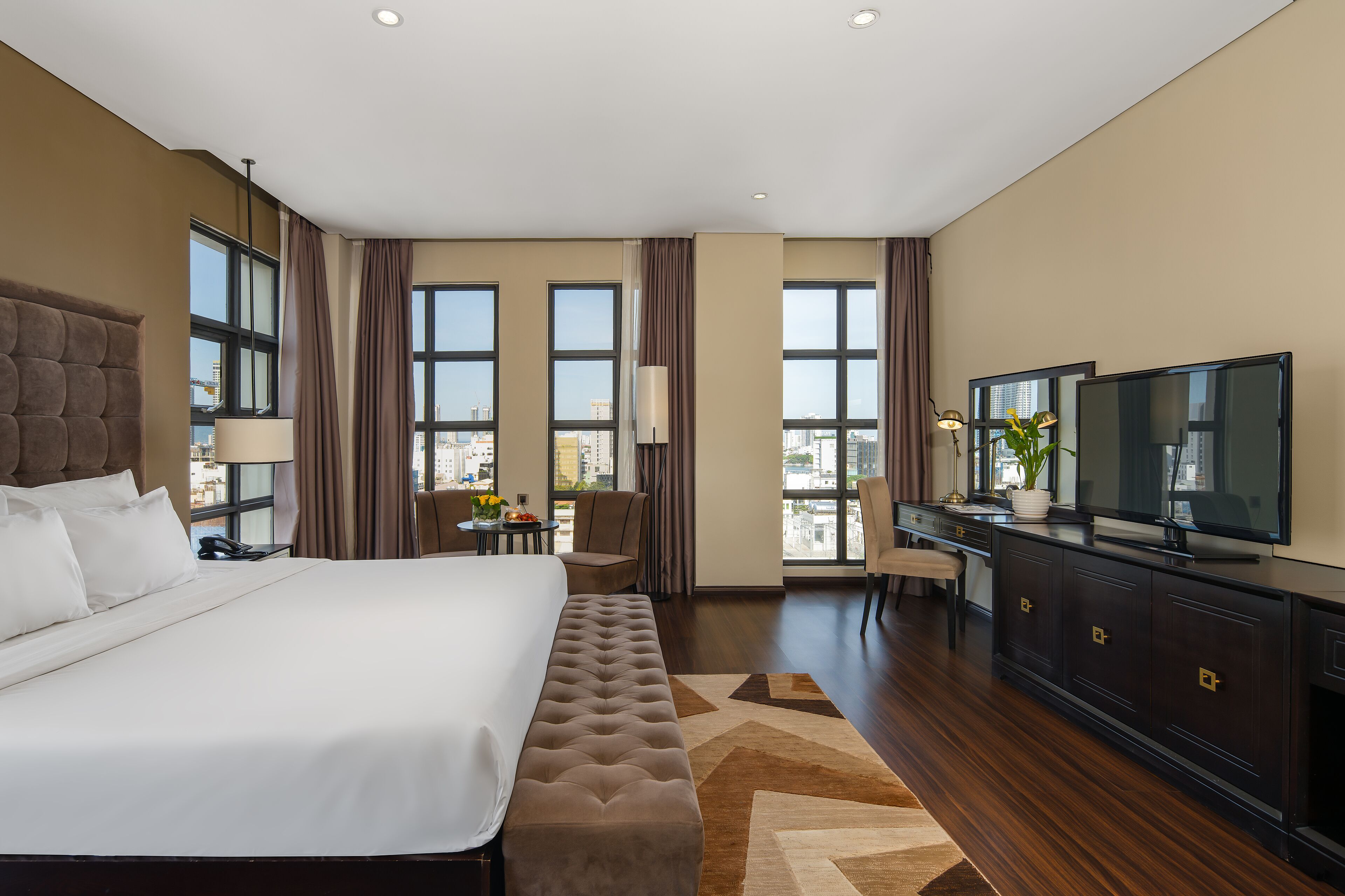 Habitación de hotel con una cama grande, televisión, escritorio y vistas a la ciudad.