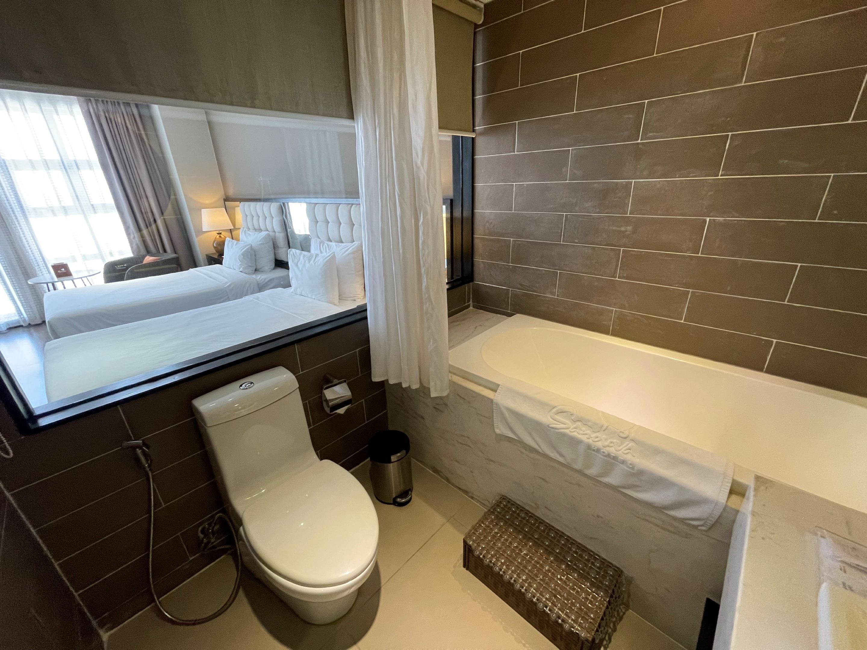 Un baño moderno con bañera, inodoro y ventana con cortinas.