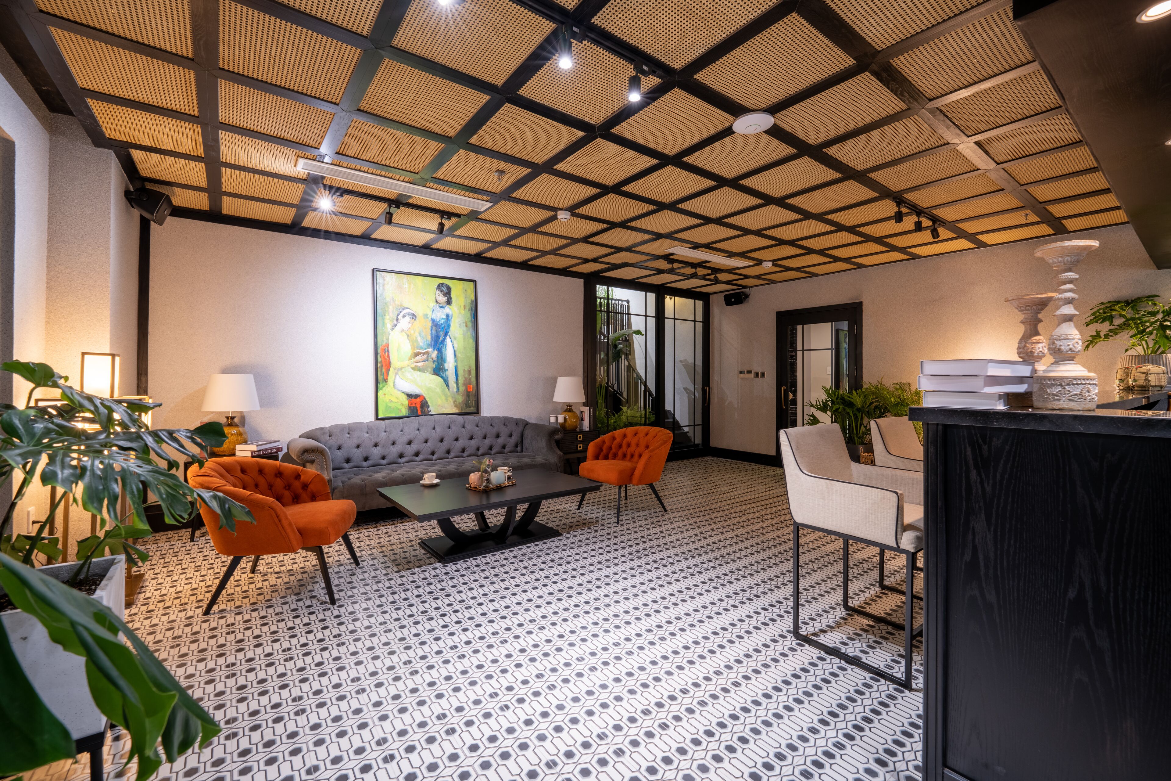 Un salon moderne avec un sol à motifs, un canapé, deux fauteuils, une table basse et un vase décoratif.