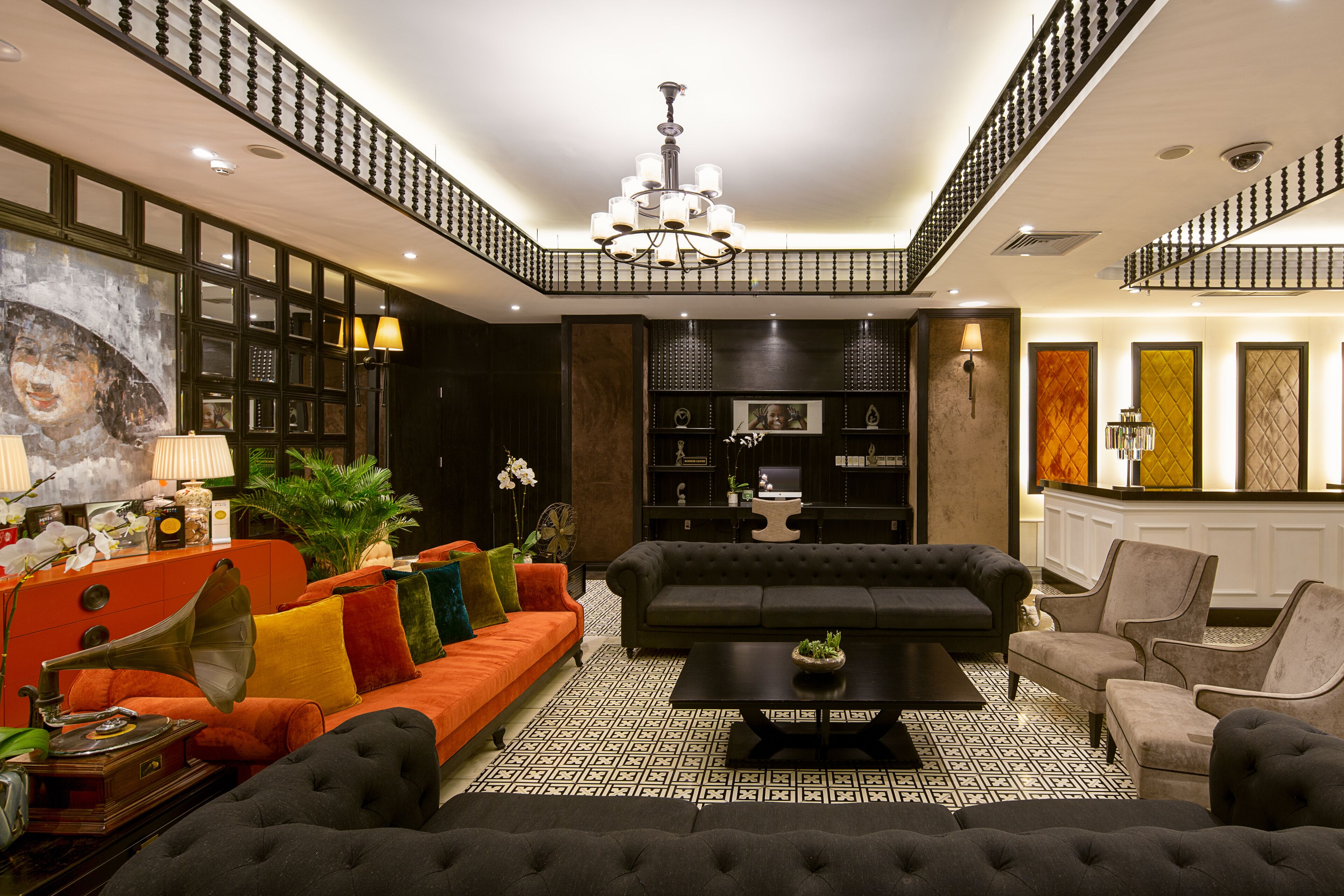 Ein geräumiges Wohnzimmer mit einem schwarzen Sofa, einem orangefarbenen Sofa und einem schwarzen Sessel. In der Mitte steht ein schwarzer Couchtisch.