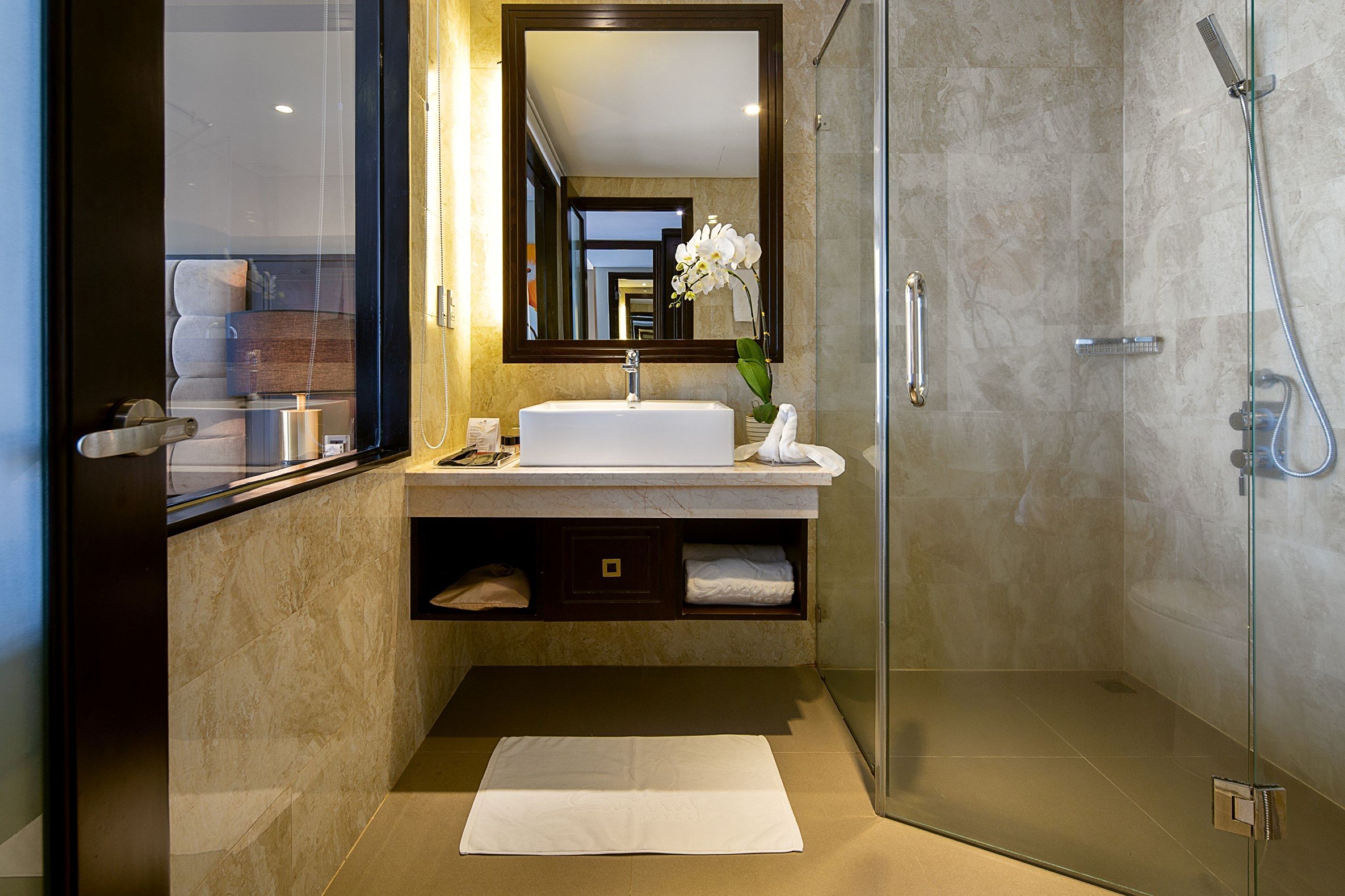 Un baño moderno con cabina de ducha de vidrio, un lavabo blanco y un espejo encima.