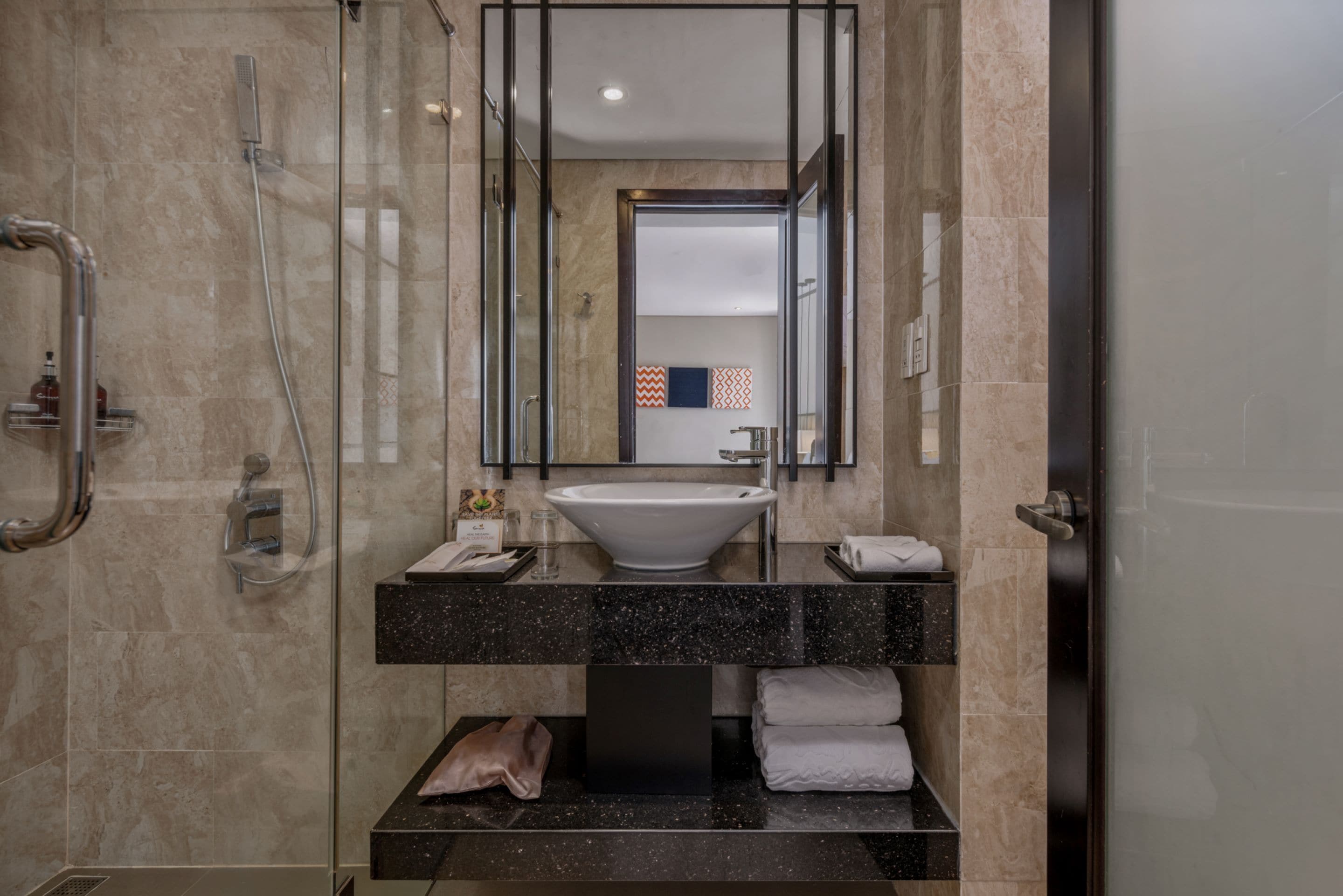 A modern bathroom with a glass-enclosed shower, a white sink, and a black countertop.