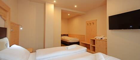 A hotel room with two beds, a TV mounted on the wall, and a wooden cabinet with a telephone.