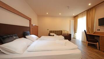 A hotel room with two beds, a desk, a chair, and a TV.