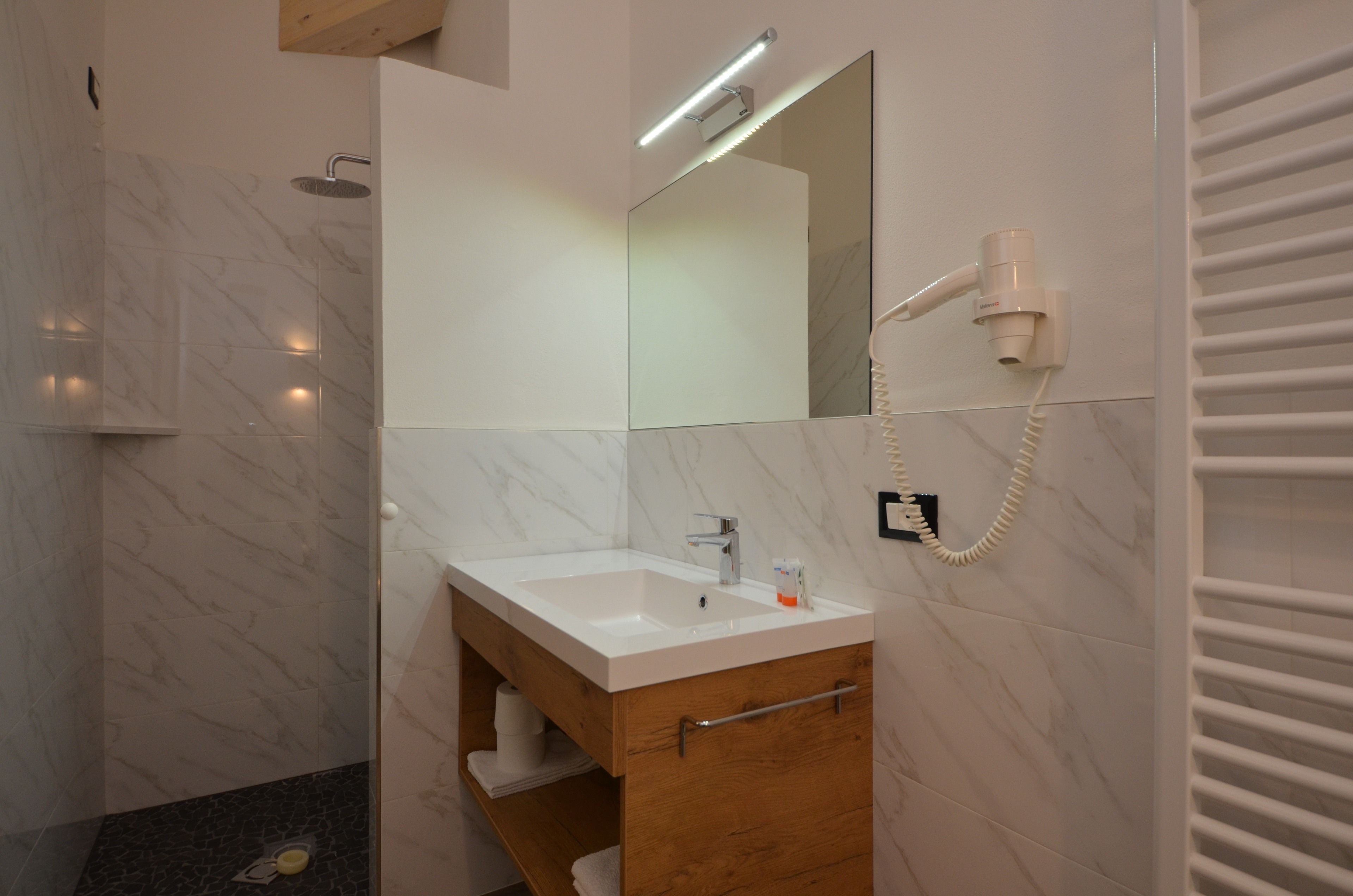 A modern bathroom with a marble vanity, a handheld hair dryer, and a towel rack.