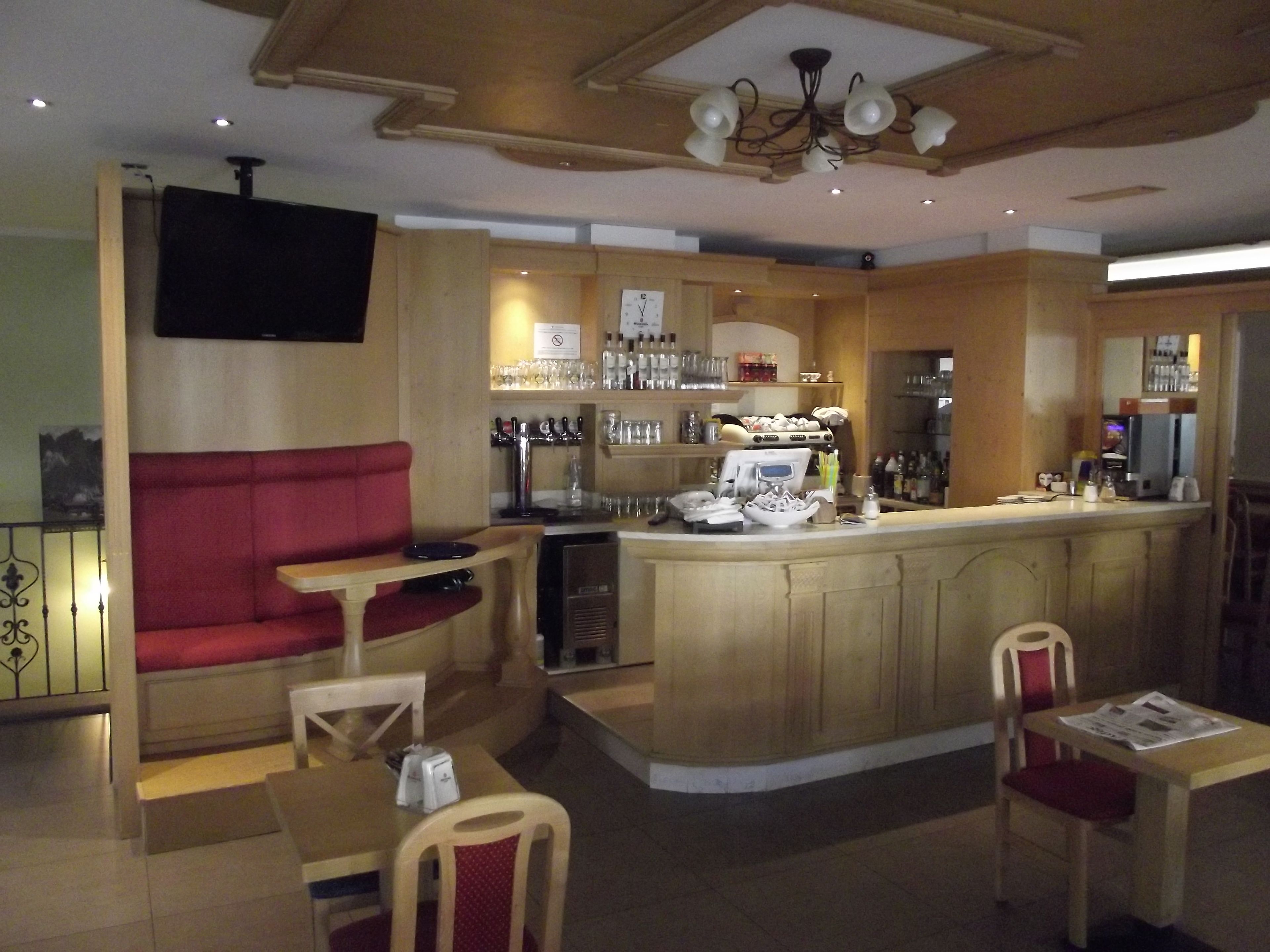A bar area with a counter, seating, and a television mounted on the wall.