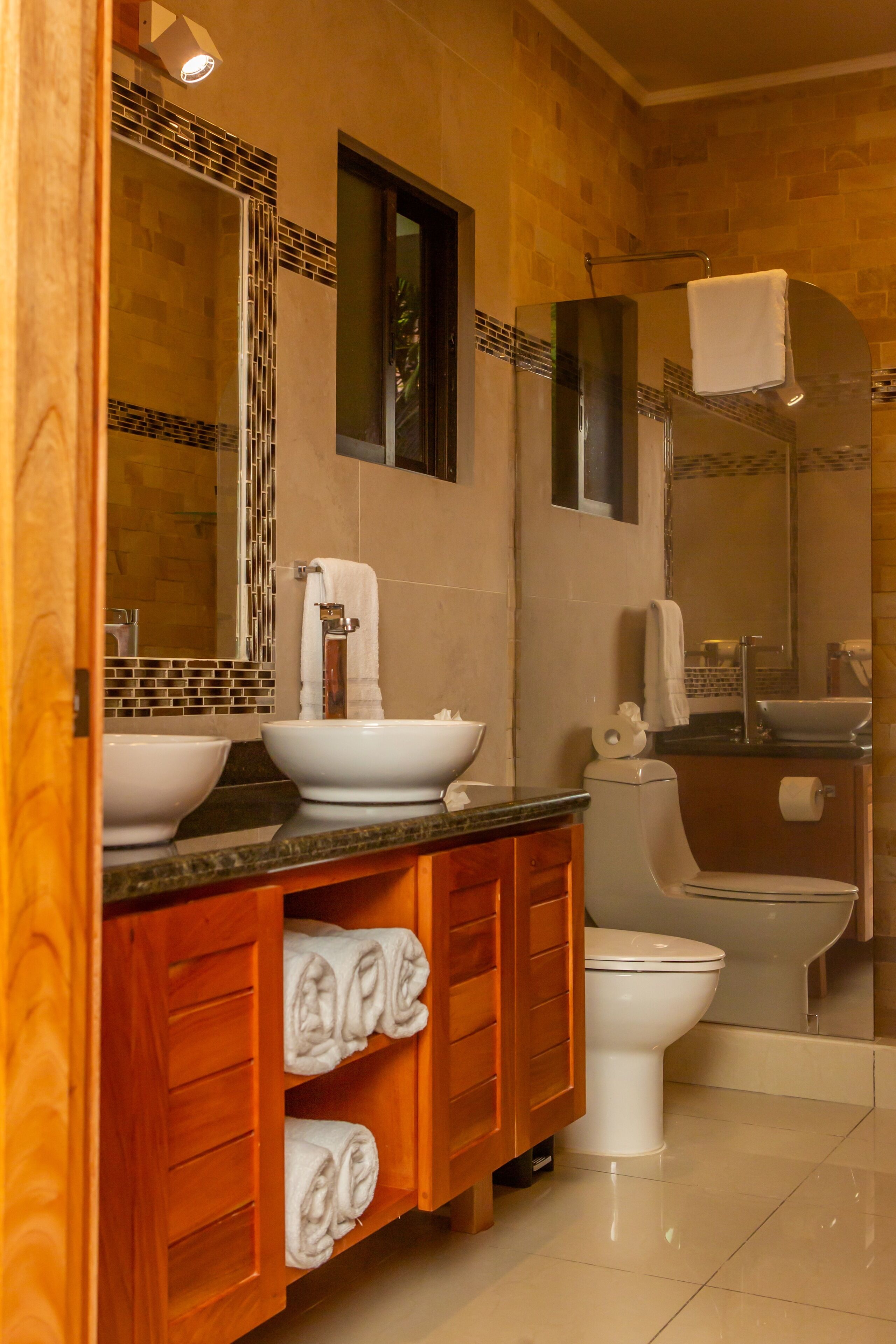 Un baño moderno con dos lavamanos, un inodoro y una ducha.