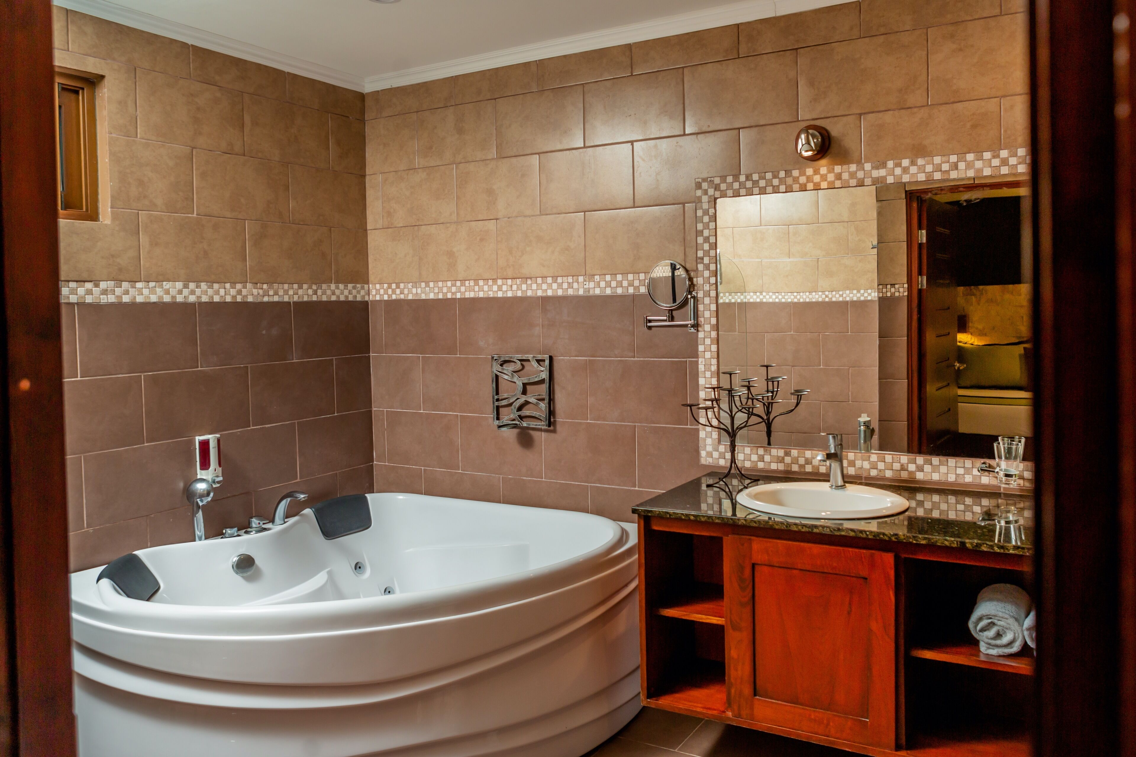 A bathroom with a large bathtub, a sink, and a mirror.