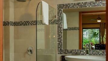A modern bathroom with a glass-enclosed shower, a large mirror, and a wooden vanity with a sink.