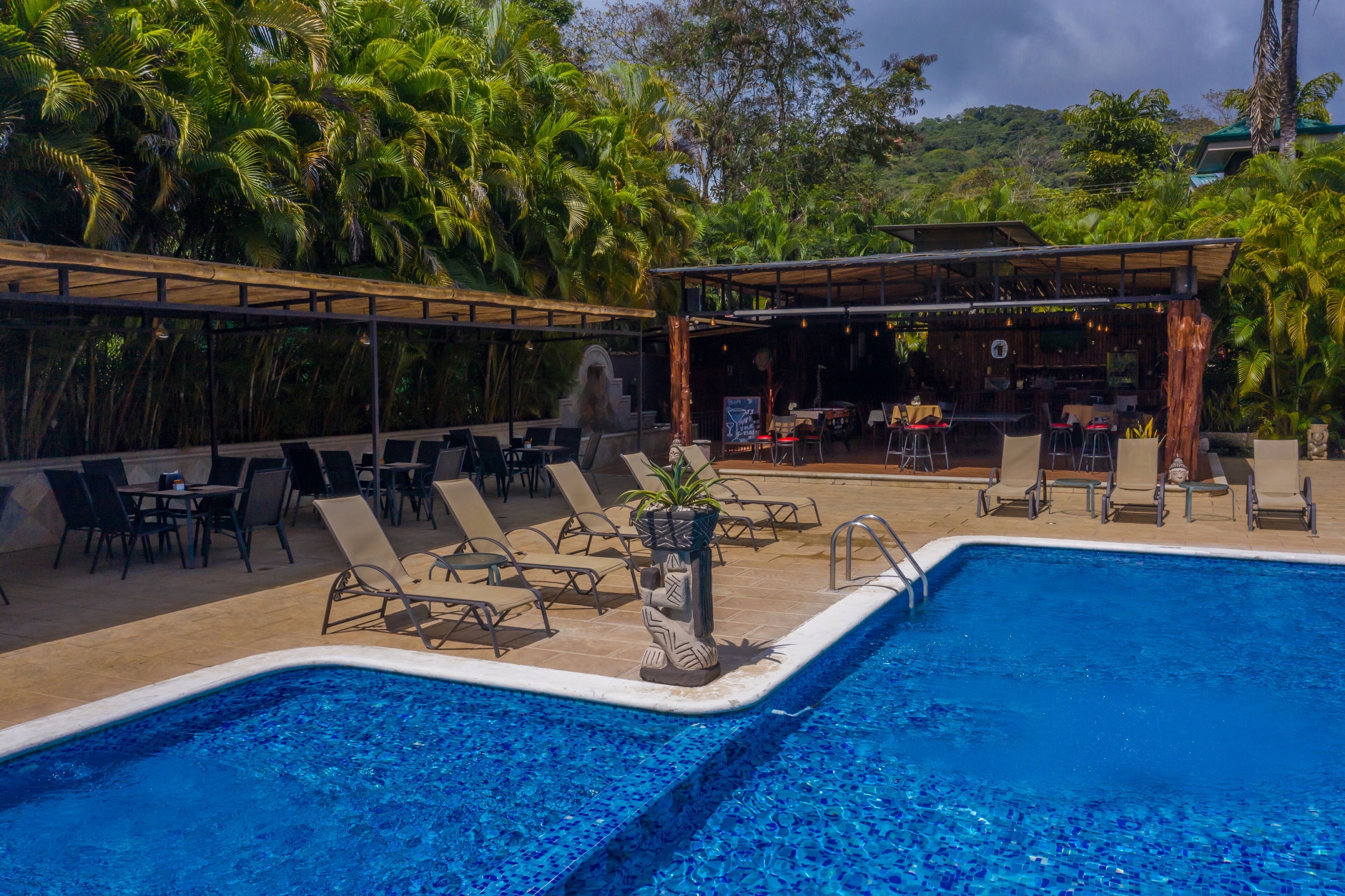 A pool area with lounge chairs and a covered seating area.
