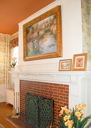 A room with a fireplace, a painting above it, and a potted plant on the mantel. - The Albanus Phillips Inn (Cambridge)