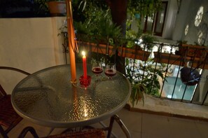 Une table ronde en verre, avec une bougie, deux verres et un chandelier rouge.