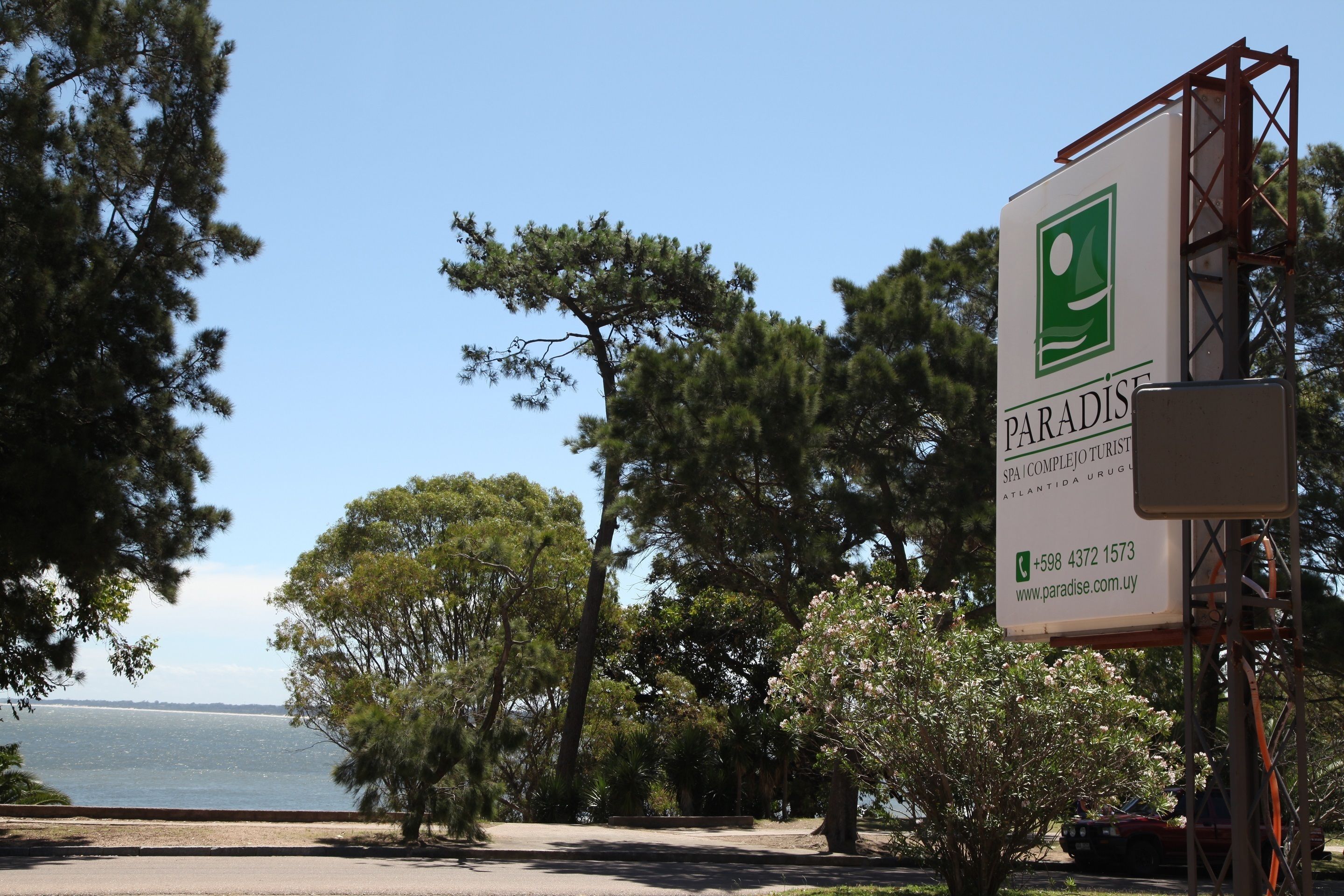A signboard for Paradise SPA & COMPLEJO TURISCO ATLANTIDA URUGUAY with contact information.
