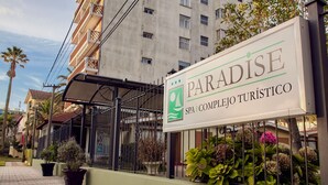 A sign for 'Paradise SPA & Complejo Turístico' with a metal fence and potted plants in front.