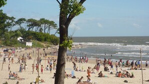 A crowded beach with people sunbathing and playing volleyball.