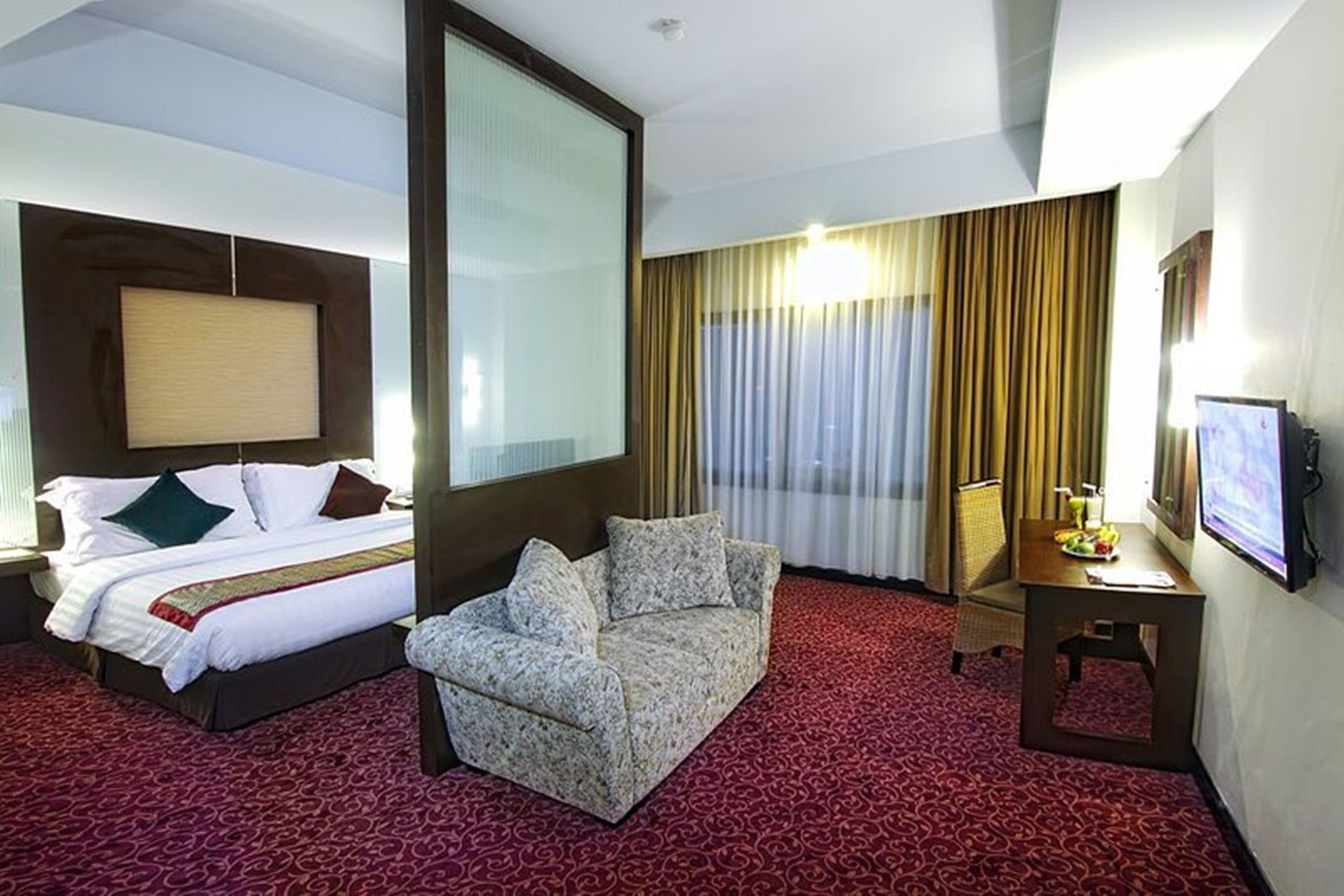A hotel room with a bed, a sofa, a desk, and a TV.