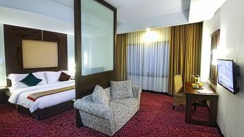 A hotel room with a bed, a sofa, a desk, and a TV.