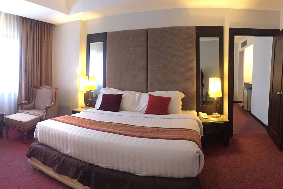 A hotel room with a large bed, two bedside lamps, a chair, and a mirror.