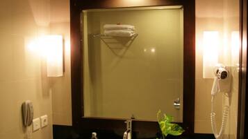 A hotel bathroom with a large sink, a mirror, a hairdryer, and a telephone.