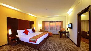 A hotel room with a large bed, bedside tables, a desk, and a television. - Hotel Pangeran Beach (Padang)