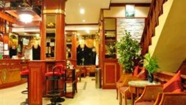 A hotel lobby with wooden furniture, a bar area, and a staircase. - Parkway Inn (Bangkok)