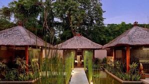 A serene hotel courtyard with thatched-roof structures, a central pathway, and a reflective water feature. - Bali Nusa Dua Hotel (Nusa Dua)