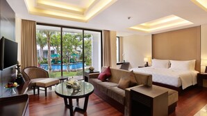 A modern hotel room with a large bed, a sofa, a glass coffee table, and a TV. - Bali Nusa Dua Hotel (Nusa Dua)