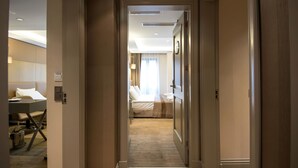 A hotel hallway leading to a bedroom with a bed, bedside table, and a lamp. - GK Regency Suites (Istanbul)