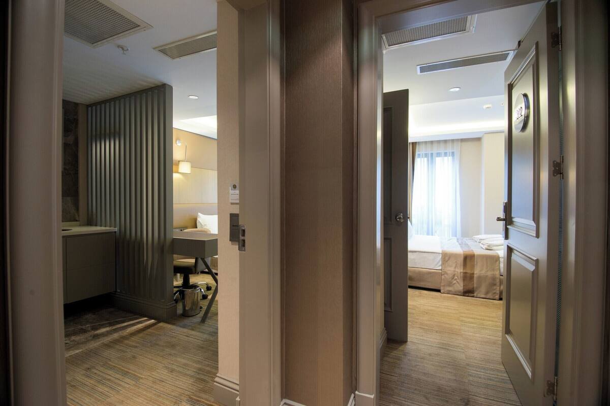A hotel room with a bed, bedside table, and a bathroom with a sink and mirror.