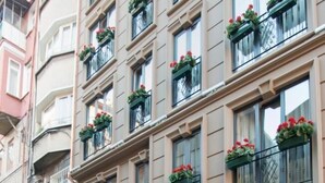 A multi-story hotel with a marble entrance, balconies with red flowers, and a staircase leading to the entrance. - GK Regency Suites (Istanbul)