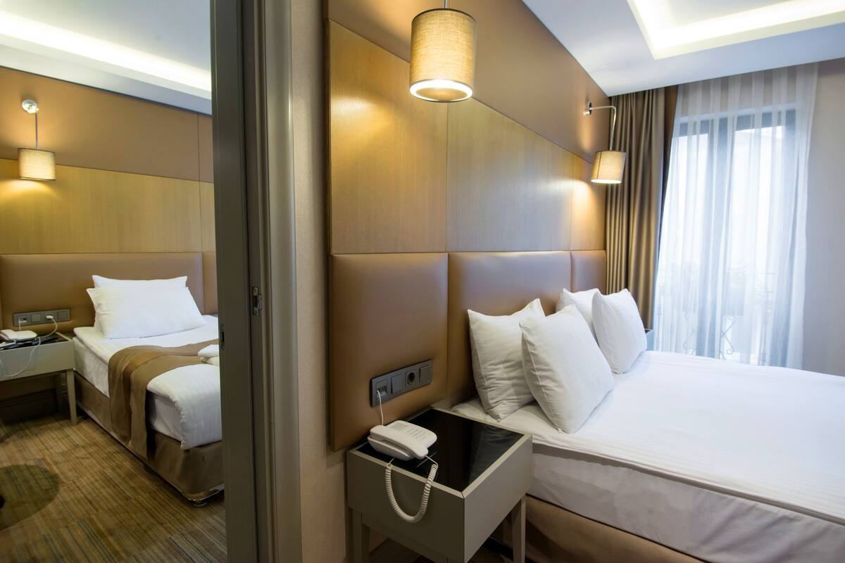 A hotel room with two beds, a bedside telephone, and a lamp on the nightstand.