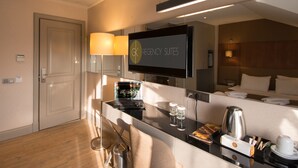 A hotel room with a TV, a desk with a laptop, a coffee maker, and a bed with pillows. - GK Regency Suites (Istanbul)