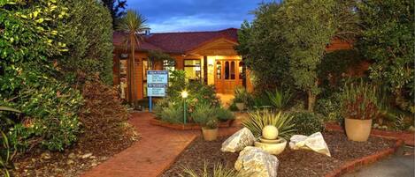 A hotel with a red-tiled roof, surrounded by landscaped gardens and a brick pathway.