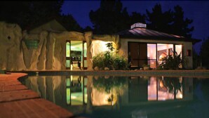 A house with a swimming pool, a stone exterior, and a large glass door. - Kimi Ora Eco Resort (Kaiteriteri)