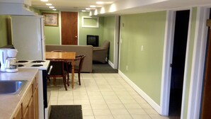 A compact kitchen with a dining area, a television, and a door leading to another room. - Relax Inn (Webster)