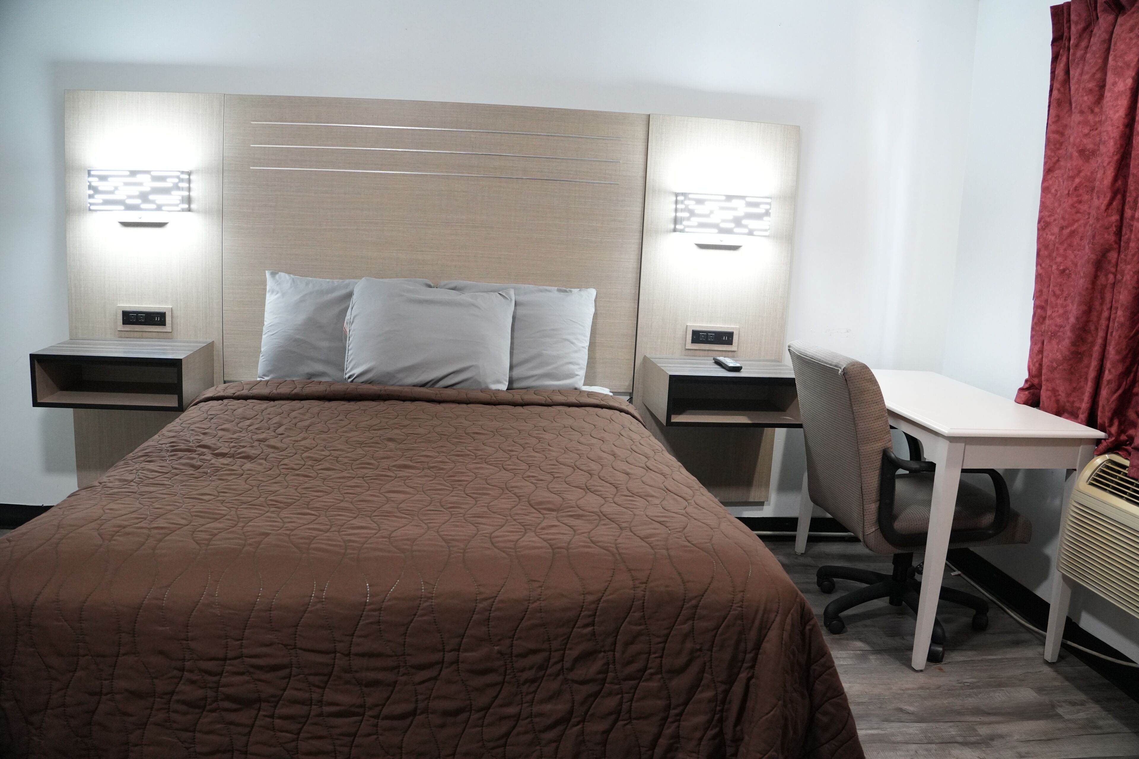 A hotel room with a bed, bedside tables, a desk, and a chair.