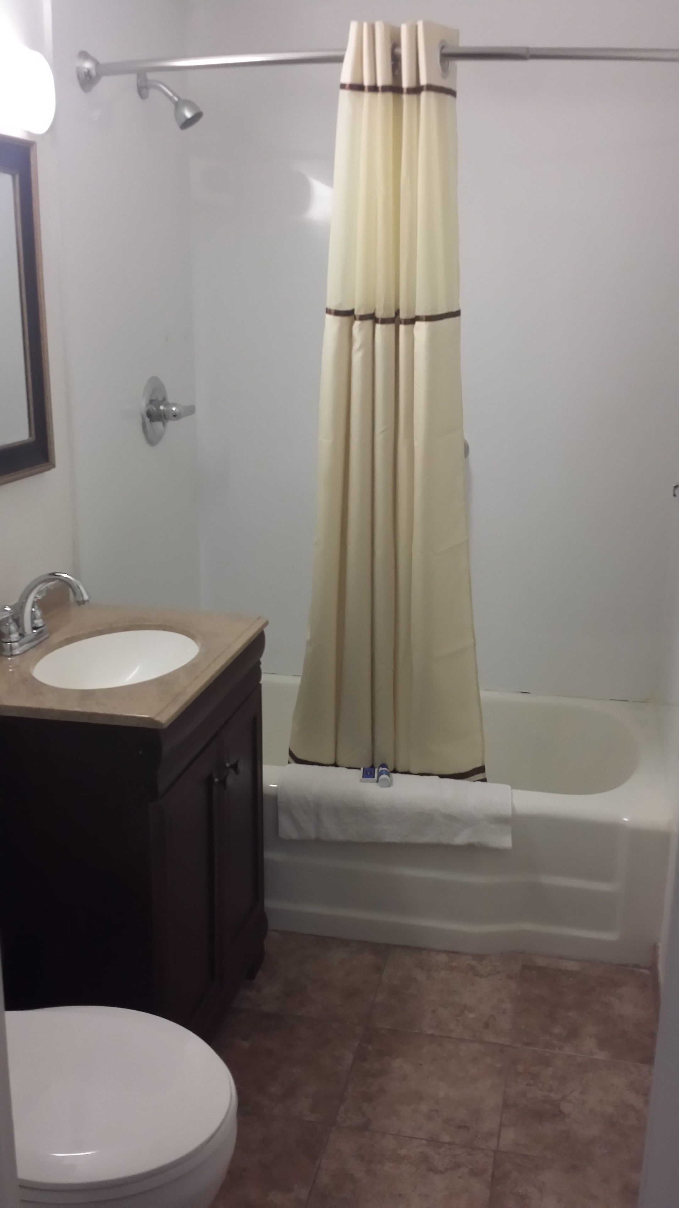 A bathroom with a bathtub, a shower curtain, a sink, and a toilet.