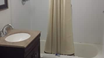 A bathroom with a bathtub, a shower curtain, a sink, and a toilet.