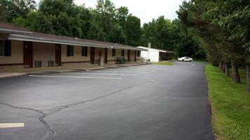 A motel with a row of rooms, a parking lot, and a car parked in front.