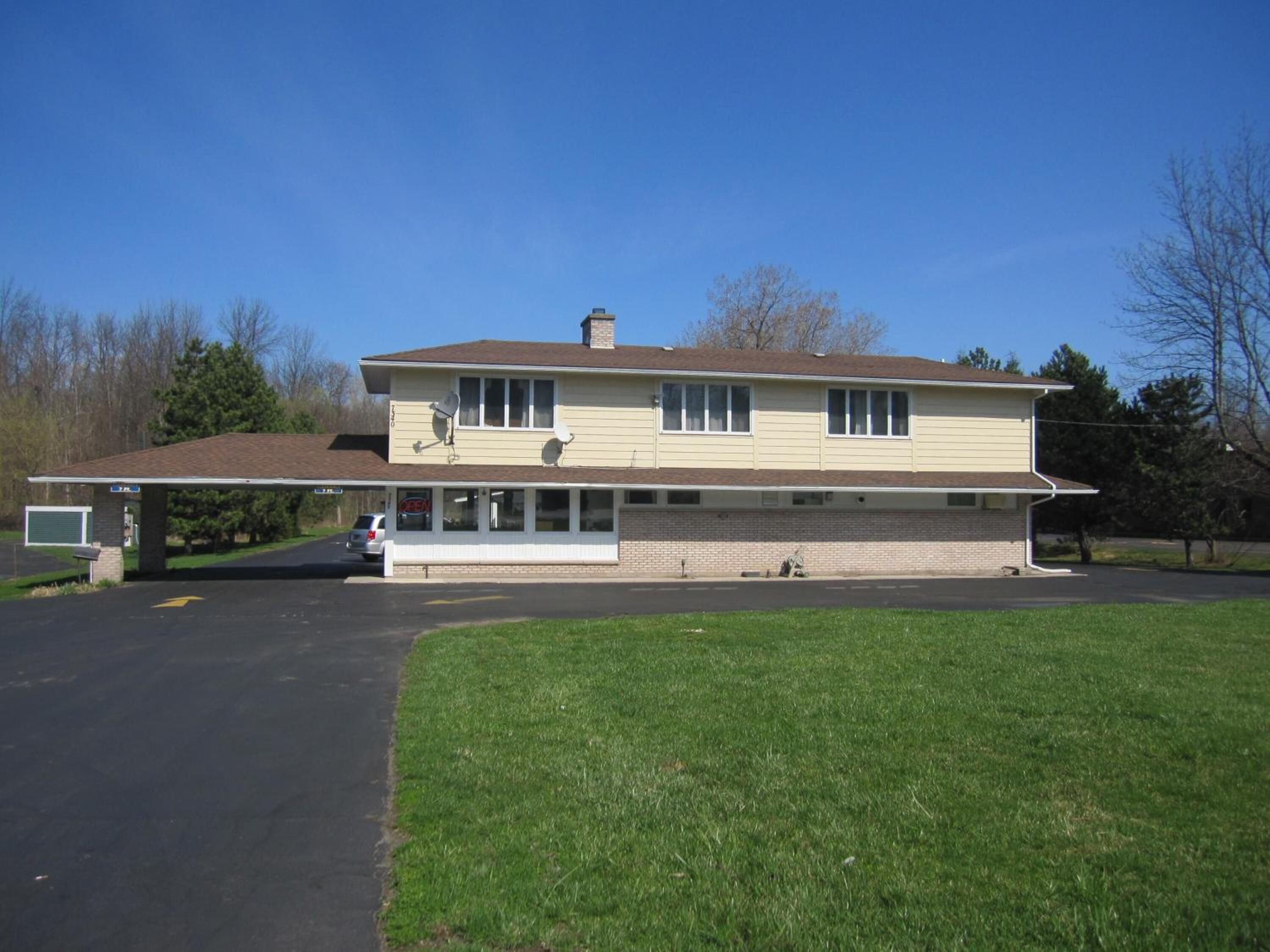 A two-story house with a garage, a covered driveway, and a lawn.