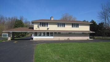 A two-story house with a garage, a covered driveway, and a lawn.