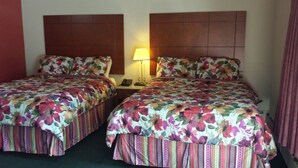 Two double beds with floral bedding, a bedside lamp, and a telephone on the nightstand. - Budget Inn Fairport (Fairport)