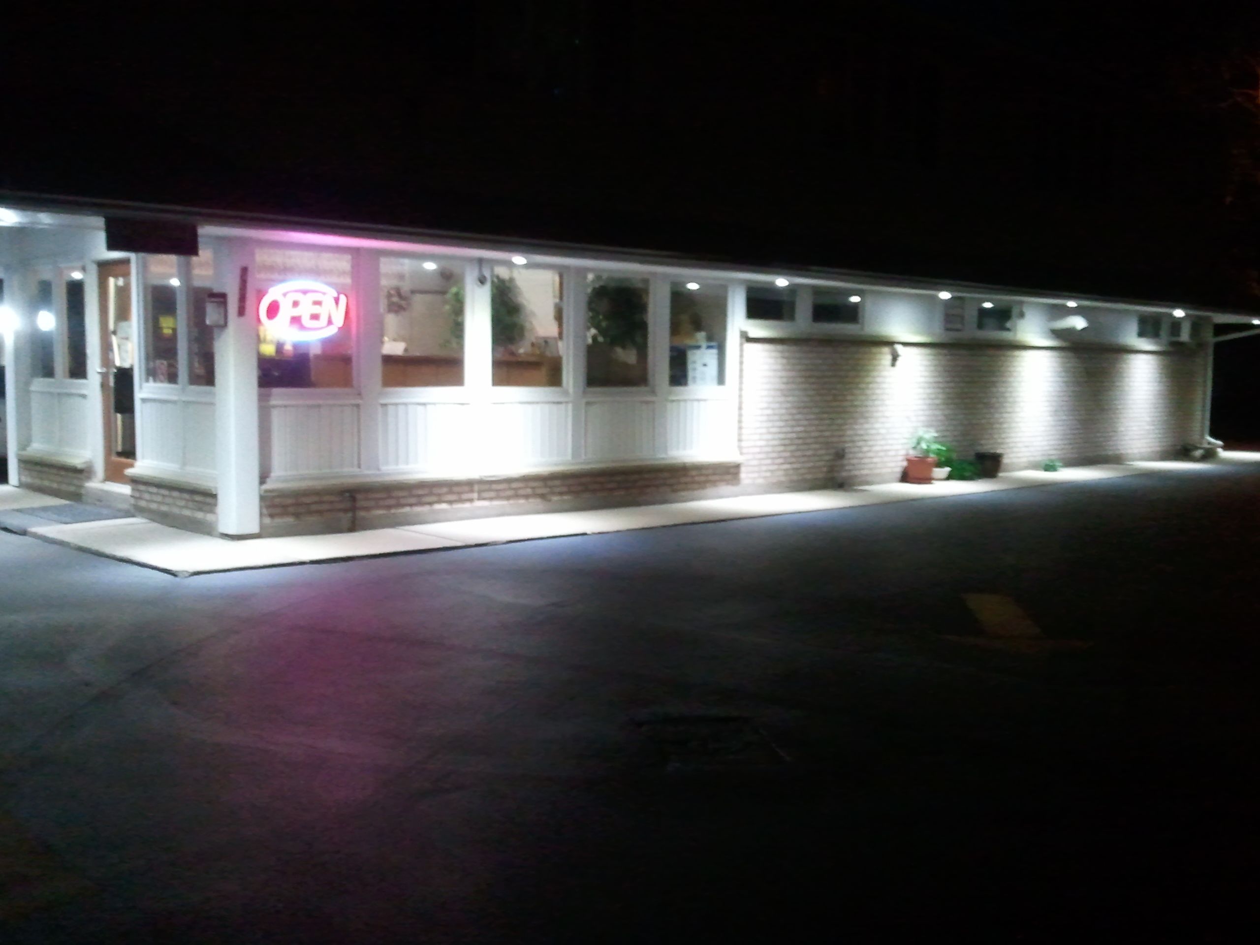 A single-story building with a porch and a neon sign.
