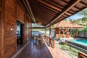 A wooden covered patio with a pool, wooden furniture, and a view of the surrounding landscape. - The Sakara Ubud Villas (Tegallalang)