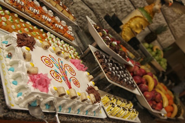 A variety of desserts and fruits displayed on trays.