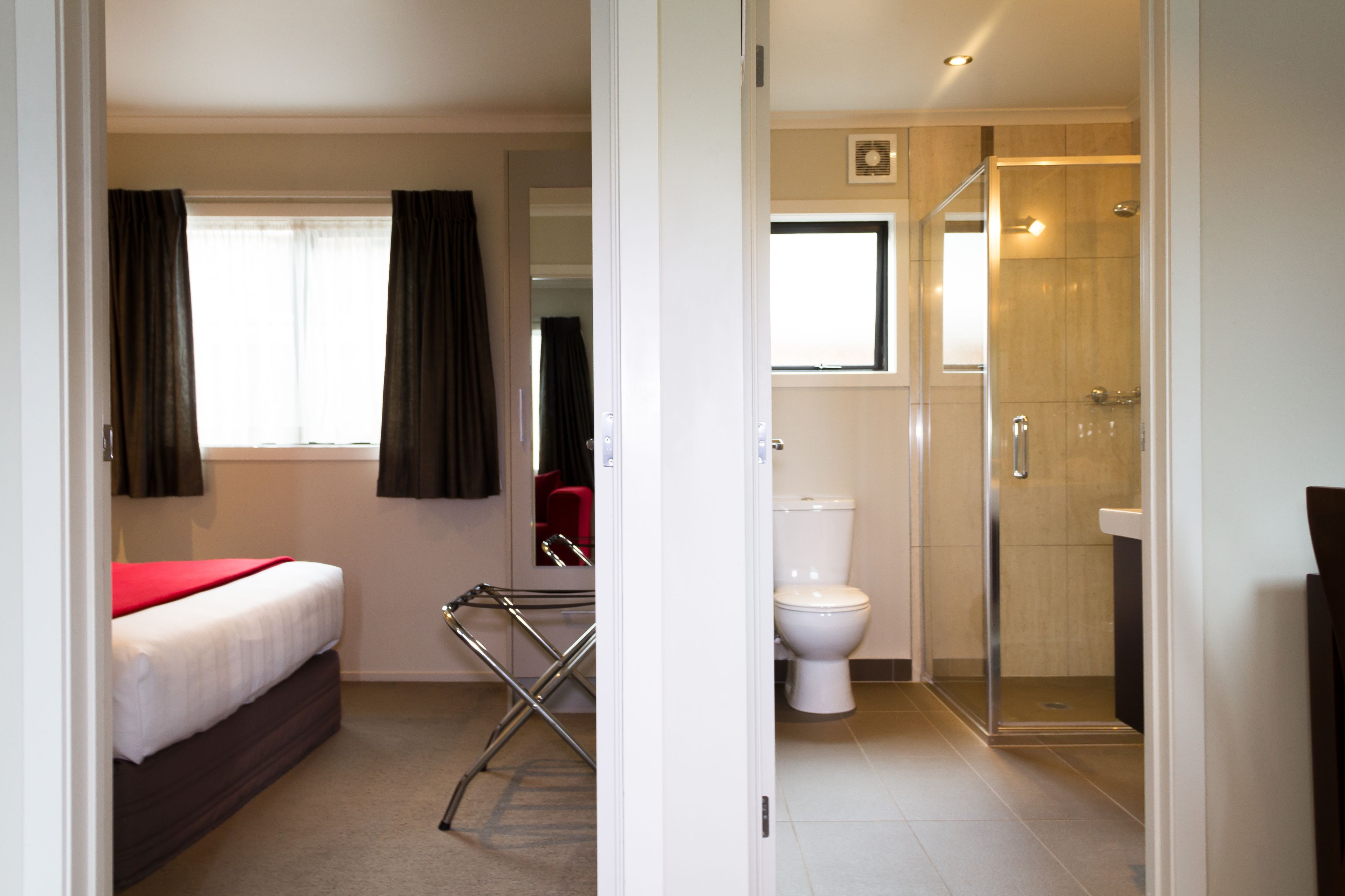 A hotel room with a bed, a shower, and a toilet.